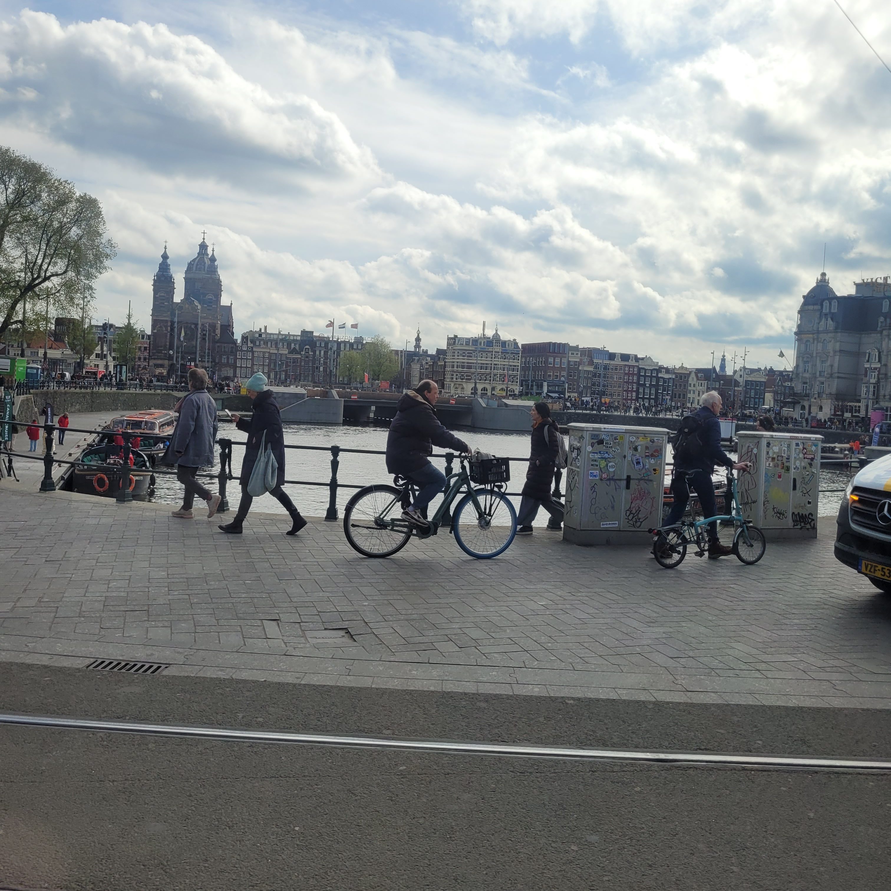 foto van een straat met fietsers en voetgangers.