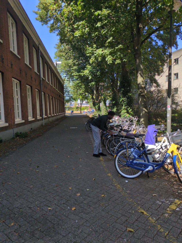 Foto van een ontwikkelaar met een laptop buiten gebouw 24 op het marineterrein Amsterdam